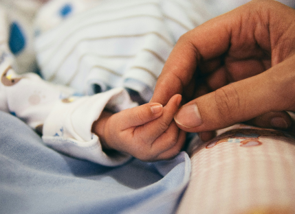 Liten bebis håller hand med vuxen